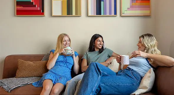 Three young women sitting on a sofa, smiling