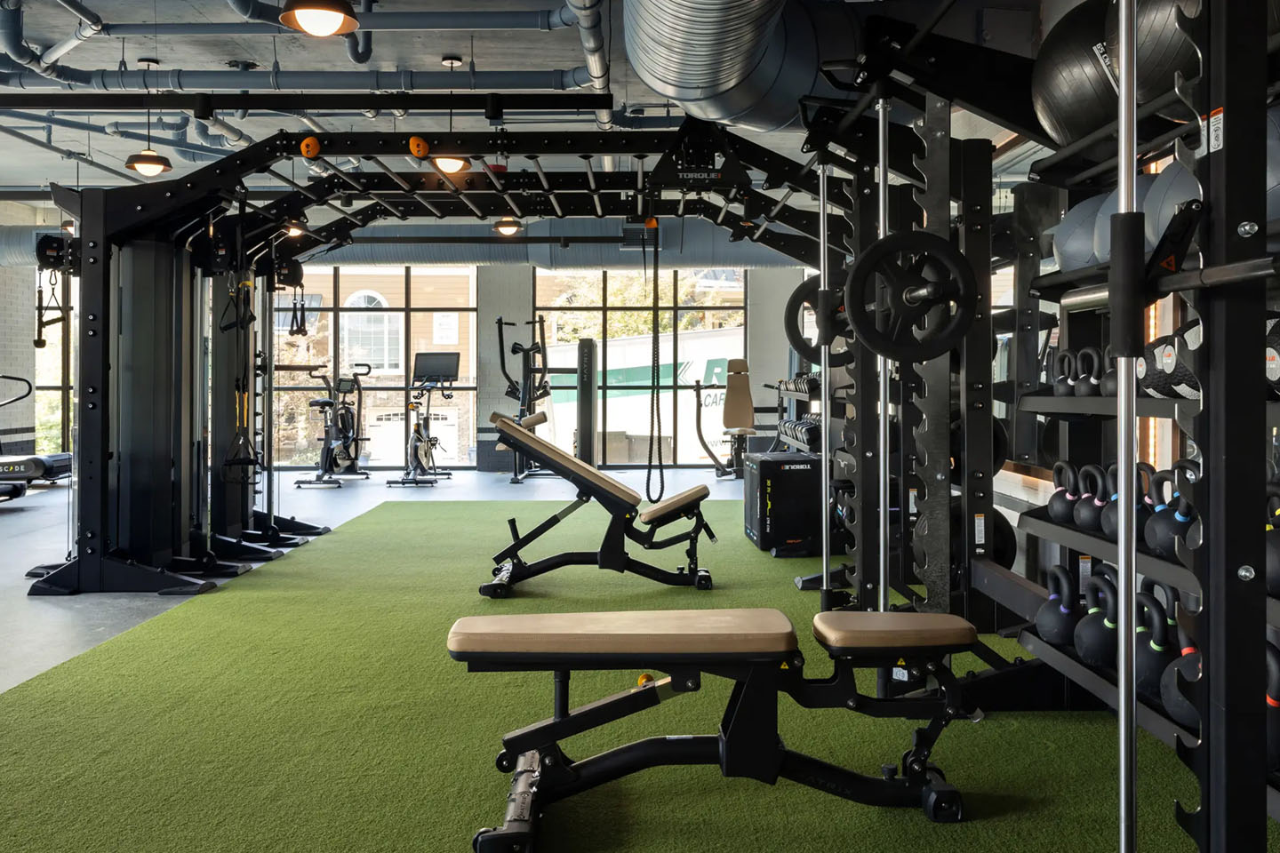 Apartment gym with turf grass, weight benches, and dynamic fitness equipment.